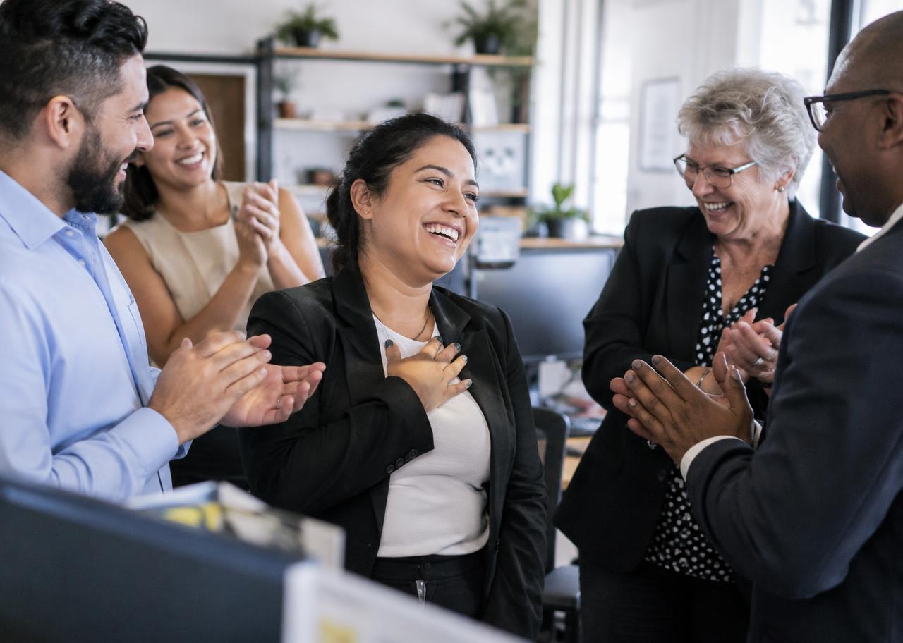 Professional being congratulated by a senior leader and her team